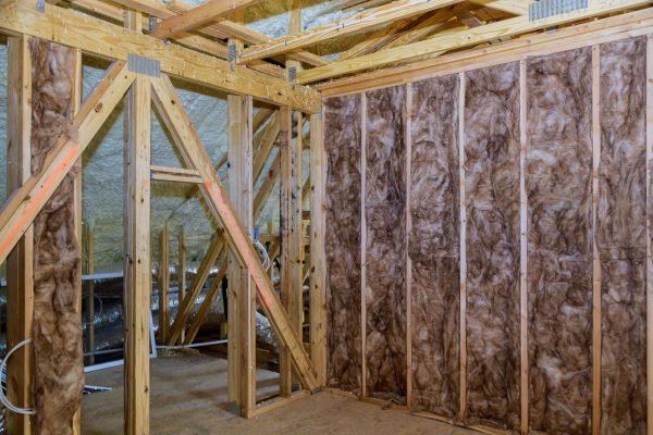 Fiberglass cold barrier insulation material in the sloping attic of a new frame house